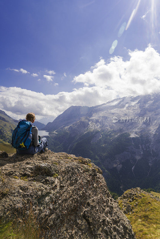 意大利北部Dolomites的Viel dal Pan小路上，一位老妇人正在欣赏美丽的Fedaia湖和Marmolada湖。